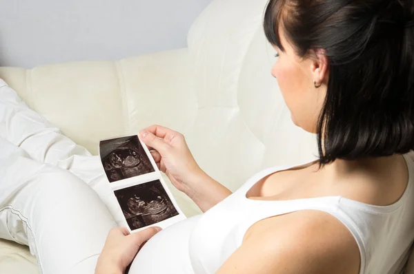 Pregnant woman looking at her baby ultrasound picture — Stock Photo, Image