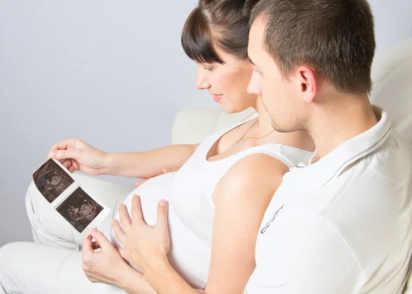 Casal jovem olhando para sua imagem de ultra-som do bebê — Fotografia de Stock