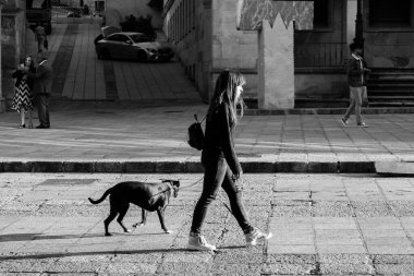SORIA, İSPA - 6 Eylül 2019: Genç bir kadın köpeğiyle birlikte şehir meydanlarından birinde yürüyor.