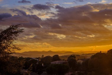 Alçak bulutlu gün batımı gökyüzü ve sarıdan kırmızıya renkler.
