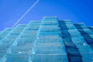 Dış görünüşü naylon kumaşla kaplı büyük bir bina yenileniyor..