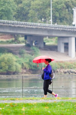 PONTEVEDRA, İSPAN - 7 Eylül 2014: Şemsiyeli hamile bir kadın, yağmurlu bir yaz günü şehir caddesinde yürüyor.