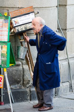 SEGOVIA, İspanya - 20 EYLÜL 2014: Kocaman eski bir kamerası olan yaşlı bir adam, şehirde bir gün çalıştıktan sonra dinleniyor.