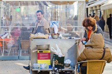LISBON, PORTUGAL - 2 Aralık 2013: Bir kadın Lizbon sokaklarındaki bir satıcıdan kızarmış kestane alır.