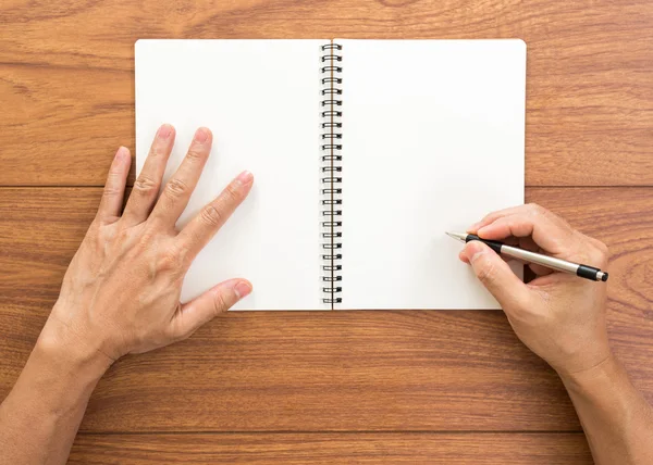 Homem mão escrevendo notebook sobre fundo de madeira — Fotografia de Stock
