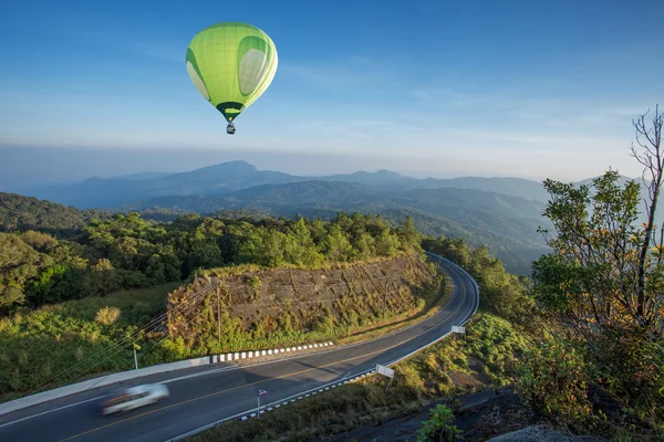 Hete luchtballon over hoge berg en over de weg — Stockfoto