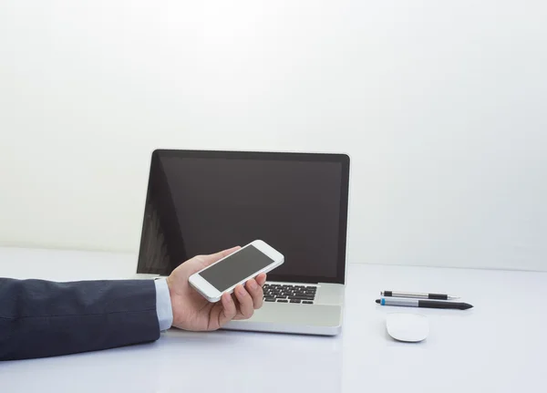 Businessman hand holding mobile phone with laptop computer backg — Stock Photo, Image