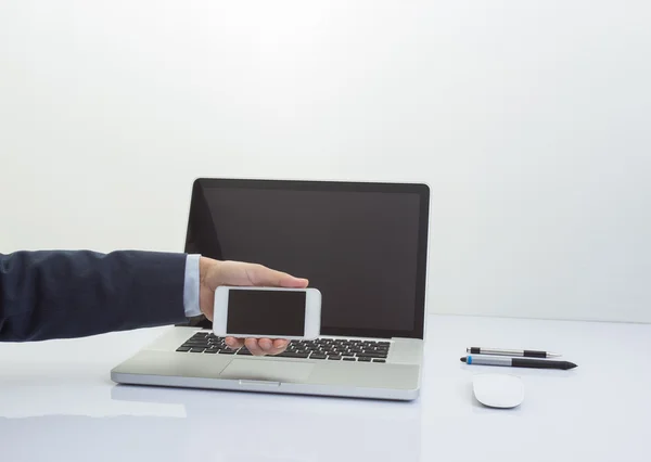 Geschäftsmann hält Handy mit Laptop in der Hand — Stockfoto