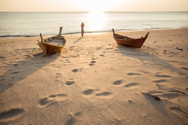 Madre che tiene il bambino alla spiaggia del tramonto con due barche — Foto Stock