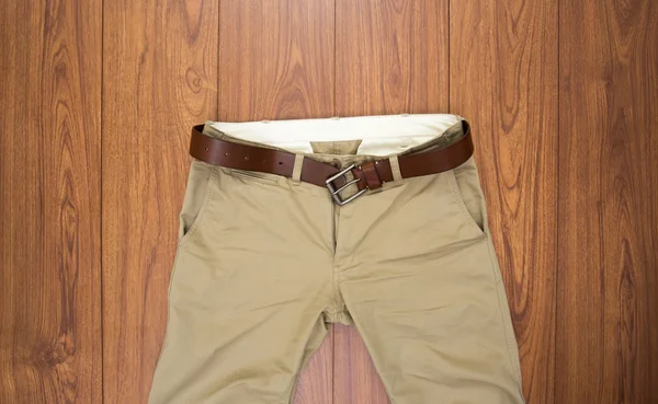 Trousers with leather belt on brown wood background — Stock Photo, Image