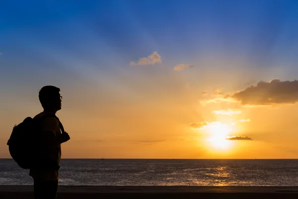 Ταξιδιώτης σιλουέτα με σακίδιο στέκεται κοντά στην παραλία στο ήλιο — Φωτογραφία Αρχείου