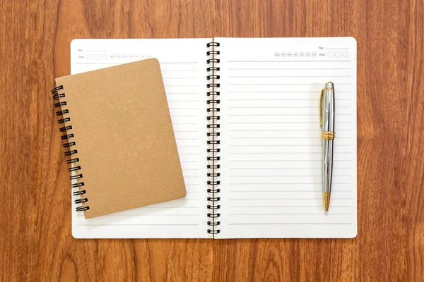 Caderno em branco com uma caneta sobre fundo de madeira — Fotografia de Stock