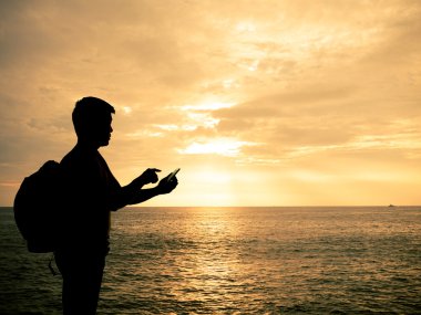 Smartphone günbatımı Plajı'nda elinde adamla siluet