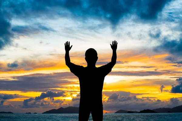 सिल्हूट आदमी सूर्यास्त समुद्र तट पर हवा में दो हाथ दिखाता है — स्टॉक फ़ोटो, इमेज