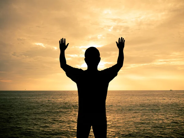 Silhouette man show two hands up in the air at sunset beach — Stock Photo, Image