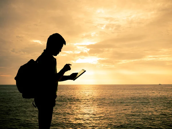 Silhouette homme avec tablette numérique dans les mains à la plage coucher de soleil — Photo