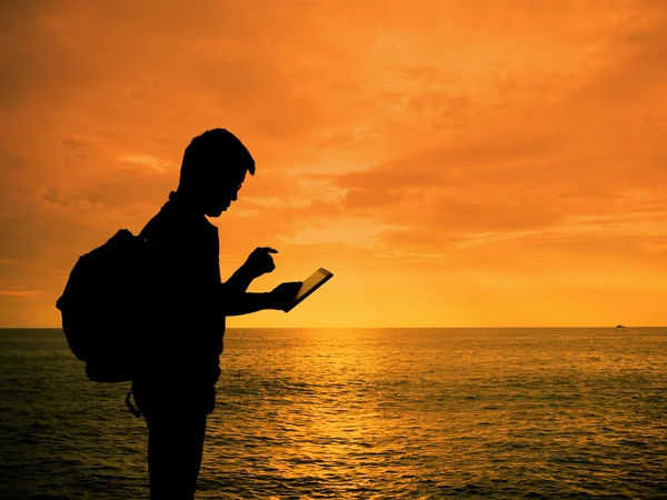 Silhouette Mann mit digitalem Tablet in der Hand am Strand von Sonnenuntergang — Stockfoto