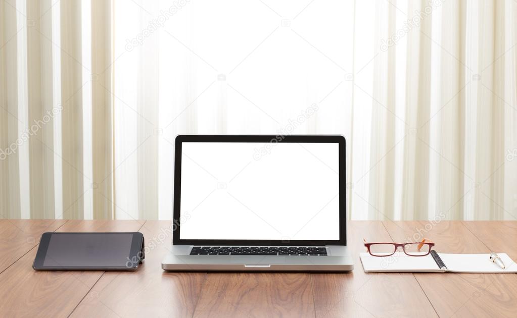 Blank screen laptop computer with office accessories on wooden t