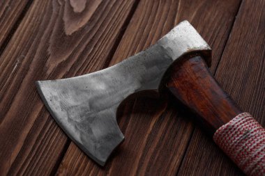 Kahverengi ahşap arka planda tahta sapı olan demir bir balta.