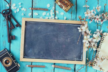 top view image of spring white cherry blossoms tree, blackboard, old camera on blue wooden table