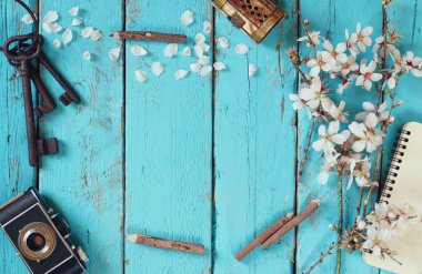 top view image of spring white cherry blossoms tree, blank notebook, old camera on blue wooden table