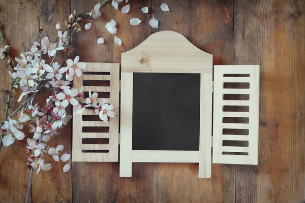 Image of spring white cherry blossoms tree next to wooden blackboard on blue wooden table. vintage filtered image — Stok fotoğraf