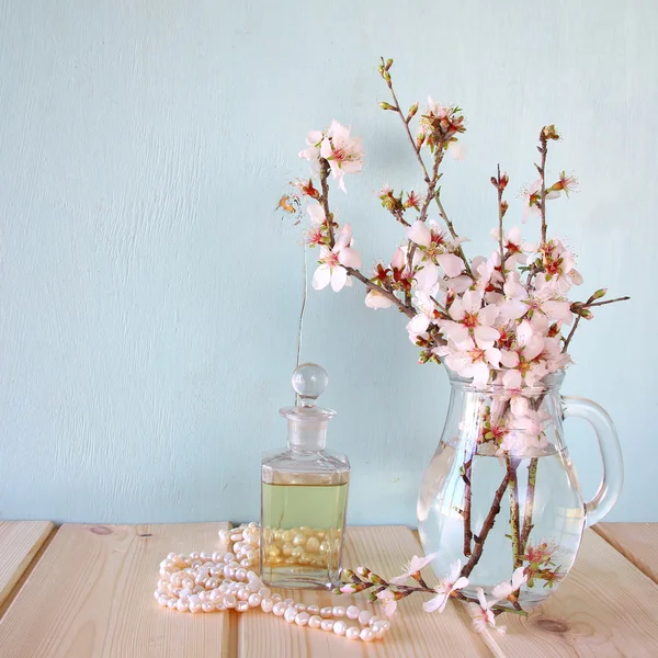 Frasco de perfume vintage fresco junto a flores blancas de primavera en la mesa de madera — Foto de Stock