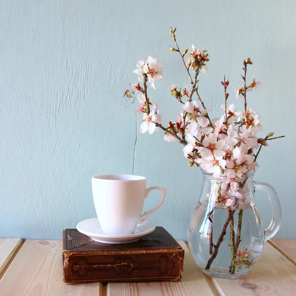 Altes Buch, Tasse Kaffee neben weißen Frühlingsblumen auf hölzerner Textur — Stockfoto