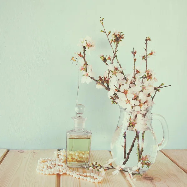Garrafa de perfume vintage fresco ao lado de flores brancas da primavera na mesa de madeira — Fotografia de Stock