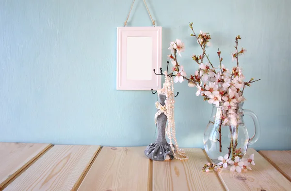 Portagioie vintage con collana di perle, cornice bianca accanto a fiori bianchi primaverili su tavolo di legno — Foto Stock