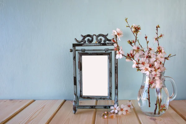 Vintage blank frame next to white spring flowers. selective focus. template, ready to put photography — ストック写真