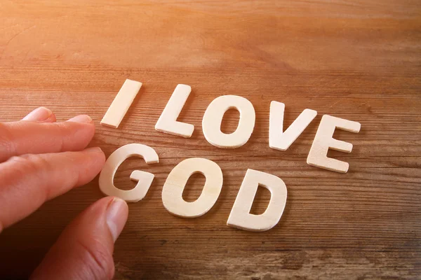Homme à la main orthographier le mot j'aime dieu à partir de lettres en bois, image de style rétro — Photo