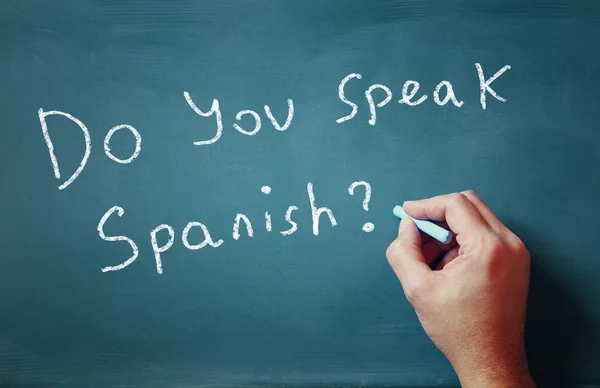 La pregunta ¿Hablas español escrito en pizarra y mano masculina —  Fotos de Stock
