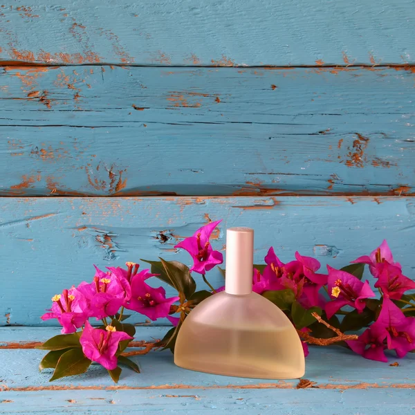 Botella de perfume vintage junto a flores de buganvillas en la mesa de madera — Foto de Stock