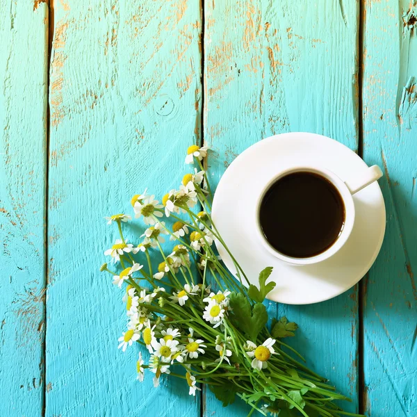 top view image of daisy flowers next to cup of coffee on blue wooden table. vintage filtered