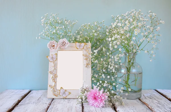 Imagen de flores rosas y blancas y marco antiguo sobre mesa de madera. plantilla, listo para poner la fotografía — Foto de Stock