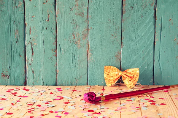 Roze partij fluit van houten tafel met kleurrijke confetti. Vintage gefilterde afbeelding — Stockfoto