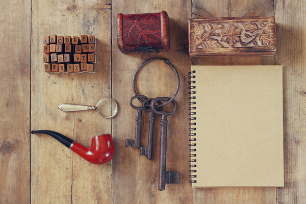 detective concept. Private Detective tools: magnifier glass, old keys, smoking pipe, notebook. top view. vintage filtered image