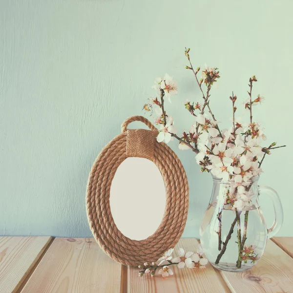 Vintage filtered and toned image of vintage blank frame next to white spring flowers. selective focus. template, ready to put photography. — Stock Photo, Image