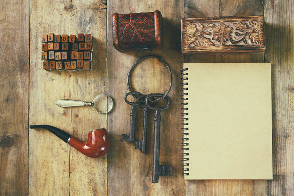 detective concept. Private Detective tools: magnifier glass, old keys, smoking pipe, notebook. top view. vintage filtered image