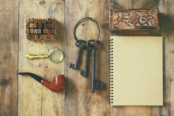 detective concept. Private Detective tools: magnifier glass, old keys, smoking pipe, notebook. top view. vintage filtered image