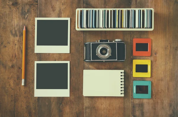 Top view of vintage camera and old slides frames over wooden table background — Stock Photo, Image