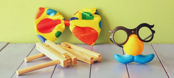 Funny glasses with moustache mask and noisemaker toy on wooden table. selective focus — Stock Photo, Image