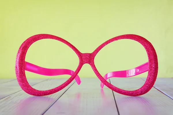 Festival retro pink eyeglasses on wooden table — Stock Photo, Image