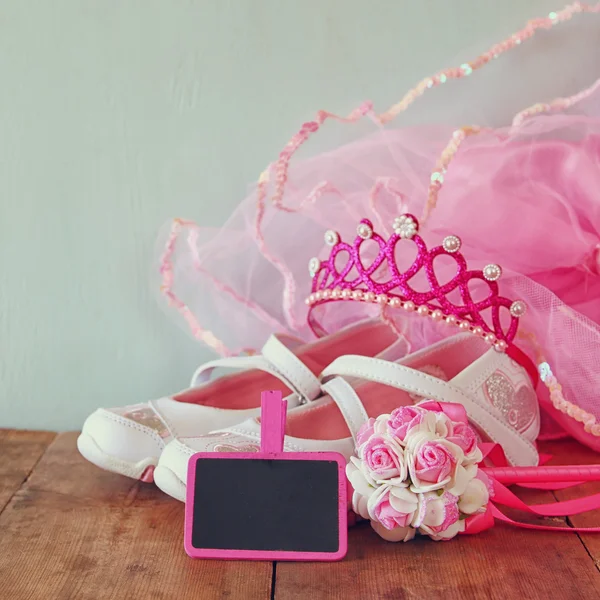Roupa de festa de meninas pequenas: sapatos brancos, coroa e varinha flores na mesa de madeira. dama de honor ou fantasia de fada — Fotografia de Stock