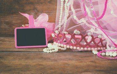 Küçük kızlar parti kıyafeti: taç ve ahşap masa üzerinde boş küçük tebeşir yanında değnek çiçekleri. nedime veya peri kostümü. vintage filtreli ve tonda