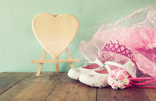 Small girls party outfit: white shoes, crown and wand flowers on wooden table. bridesmaid or fairy costume. vintage filtered — Stockfoto
