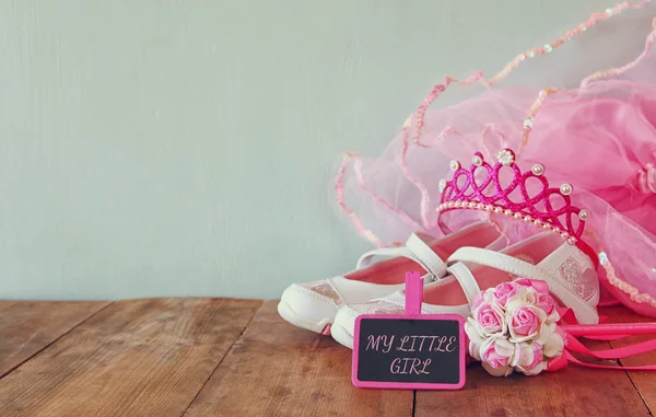 Traje de fiesta para niñas pequeñas: zapatos blancos, corona y flores de varita junto a una pizarra pequeña con la frase MY LITTLE GIRL: sobre una mesa de madera. dama de honor o disfraz de hada. recubrimiento de purpurina — Foto de Stock