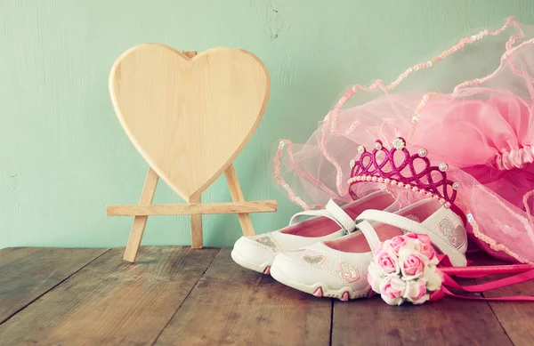 Small girls party outfit: white shoes, crown and wand flowers on wooden table. bridesmaid or fairy costume. vintage filtered — Stock Photo, Image