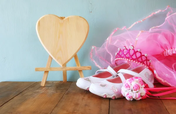 Small girls party outfit: white shoes, crown and wand flowers on wooden table. bridesmaid or fairy costume. vintage filtered — 图库照片